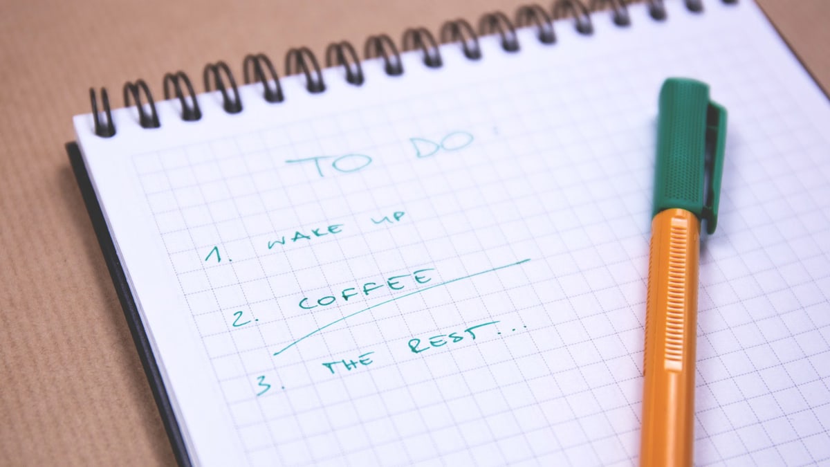 Handwritten to-do list on graph paper notebook with pen. Ideal for organizing tasks.